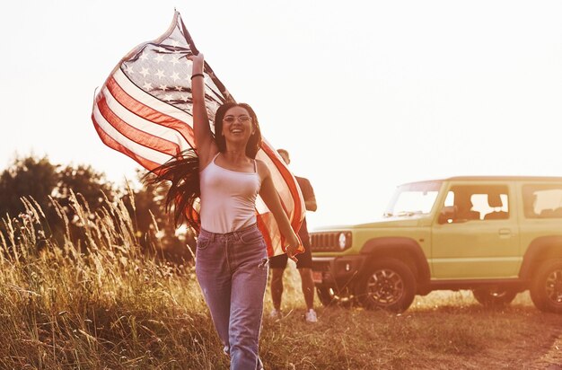 Vrienden hebben een leuk weekend buiten in de buurt van hun groene auto met Amerikaanse vlag