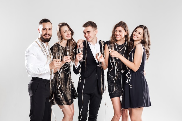 Vrienden in stijlvolle elegante kleding glimlachen samen en houden glazen champagne in handen