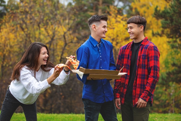 Vrienden jonge grappige mooie genieten van pizza en gezelligheid op een picknick in de natuur samen