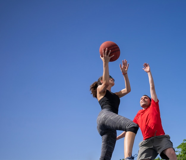 Foto vrienden jongen en meisje hebben plezier en spelen basketbal