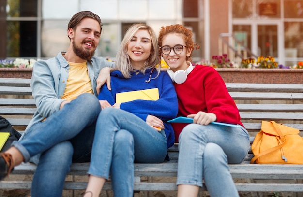 Vrienden kijken naar camera zittend op de Bank na studies