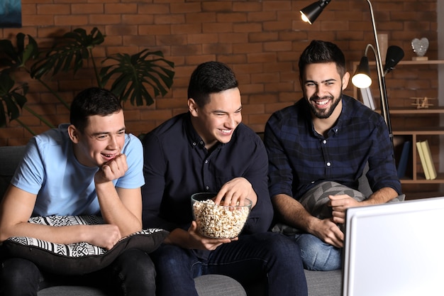 Vrienden kijken naar komedie op tv en thuis popcorn eten