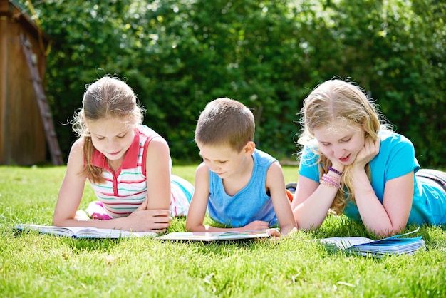 Vrienden kinderen lezen van boeken outdoori op gras