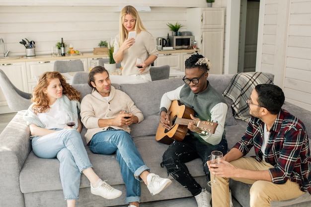 Vrienden luisteren naar Man gitaar spelen