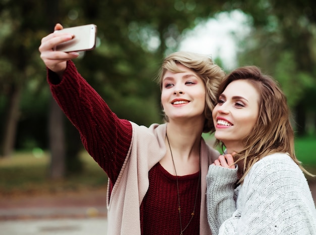 Vrienden maken selfie. Twee mooie jonge vrouwen selfie maken in herfst park.