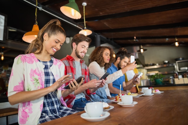 Vrienden met behulp van hun mobiele telefoons in restaurant