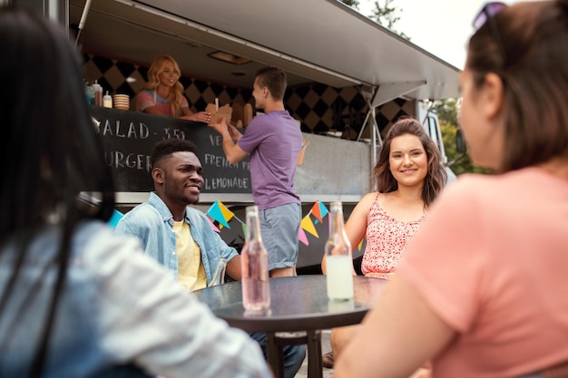 Foto vrienden met dranken zitten aan tafel bij een food truck