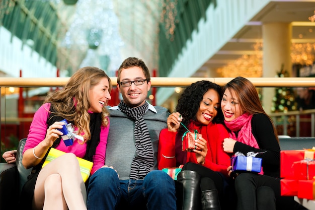 Vrienden met kerstcadeautjes en tassen in winkelcentrum