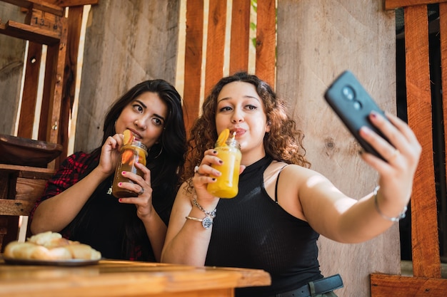 Vrienden nemen selfies die naar de camera kijken en genieten van een koel drankje.