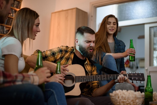 Vrienden op een huisfeest gitaar spelen en plezier maken