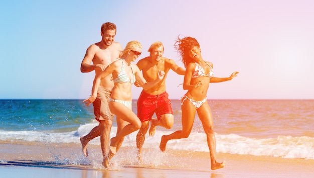 Vrienden op strandvakantie die door oceaan lopen spelen