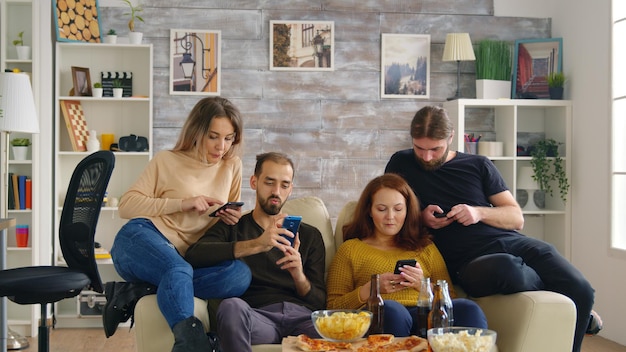 Vrienden op telefoons in gezellige lichte woonkamer.