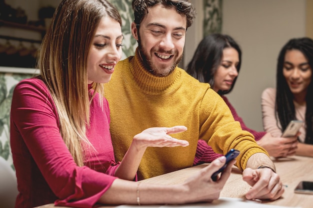 Vrienden reünie feest binnen met een groep jongeren die thuis smartphones gebruiken