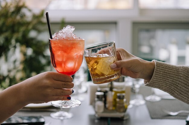 Vrienden roosteren met glazen whisky en aardbeiencocktail