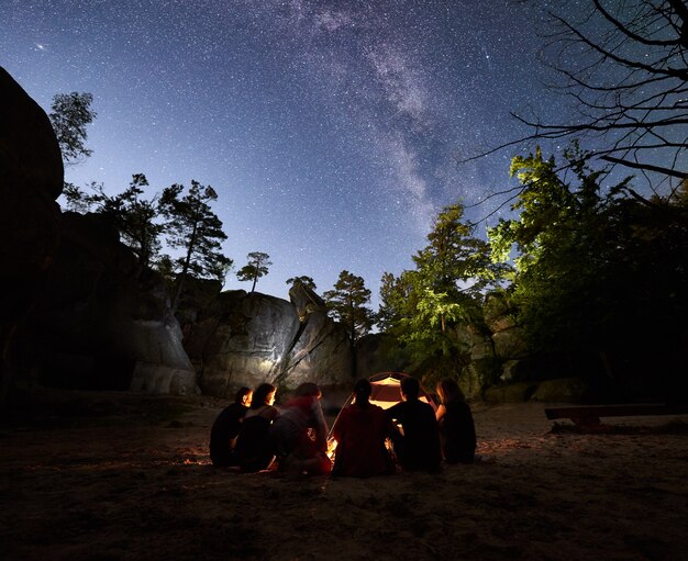 Vrienden rusten 's nachts naast kampvuur