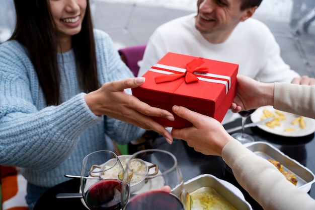Foto vrienden wisselen cadeau uit tijdens een reünie tijdens de lunch