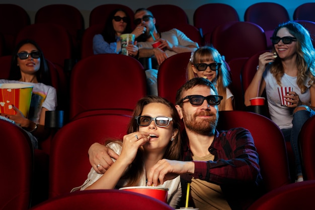 Vrienden zitten in bioscoop kijken film eten popcorn en drinkwater.