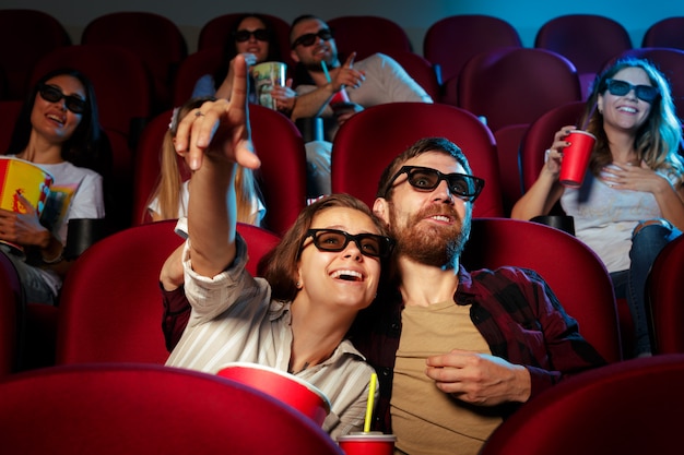 Vrienden zitten in de bioscoop kijken film eten popcorn en drinkwater.