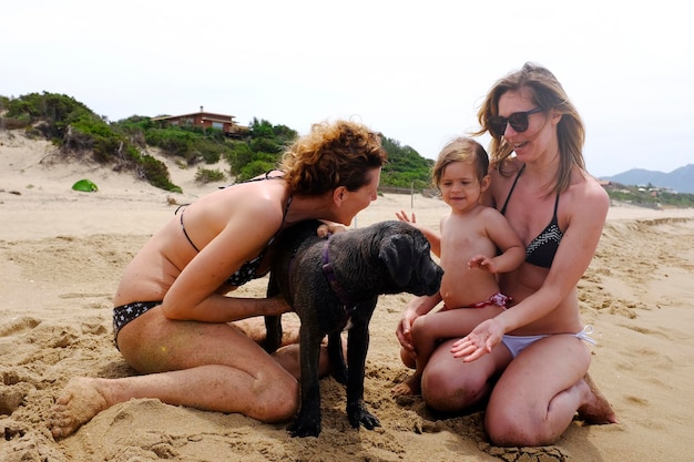 Foto vrienden zitten op het zand op het strand tegen de lucht.