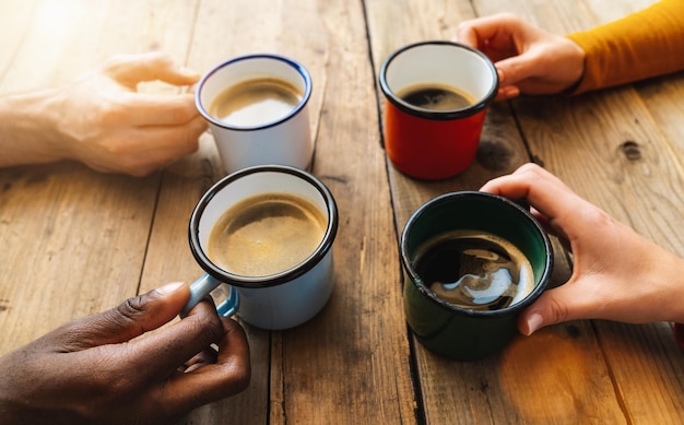 Vriendengroep die cappuccino drinkt bij koffie in een bar-restaurant - Mensenhanden juichen en roosteren - Sociaal bijeenkomstconcept met witte en zwarte mannen en vrouwen samen