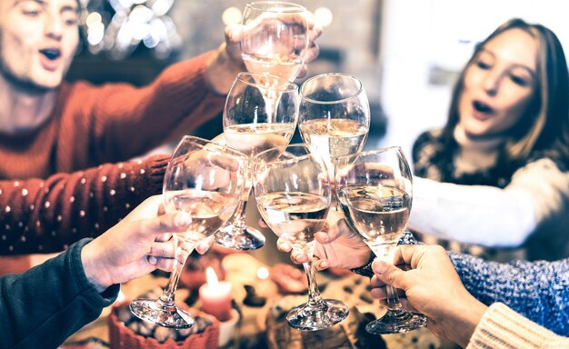 Vriendengroep die Kerstmis viert die champagnewijn roostert tijdens het thuisdiner