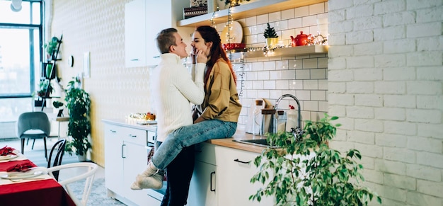 vriendin en knappe vriend in truien knuffelen in de keuken