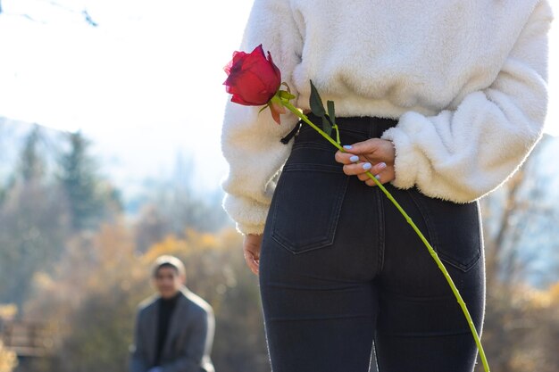 Vriendin verbergt een verrassingsroos voor haar vriend Meisje verbergt een roos voor haar vriend op valentijnsdag