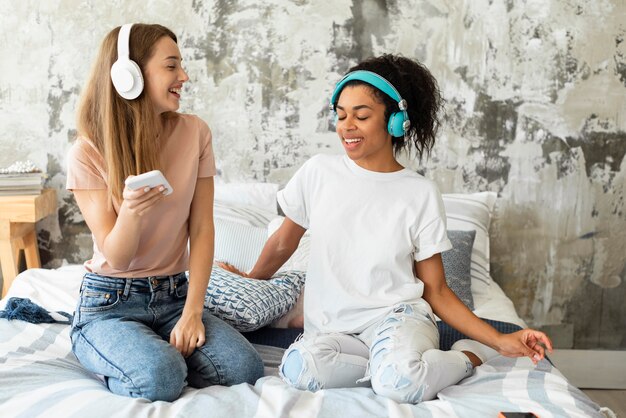 Vriendinnen dansen samen op bed thuis