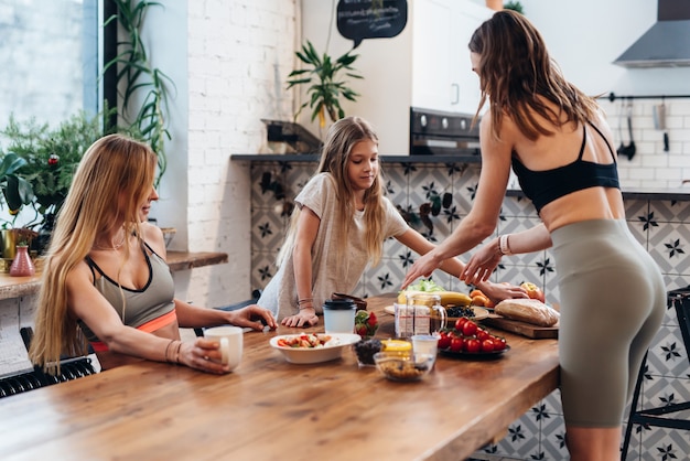 Vriendinnen en zusje maken een lichte maaltijd van groenten, fruit en salade als tussendoortje na de training.