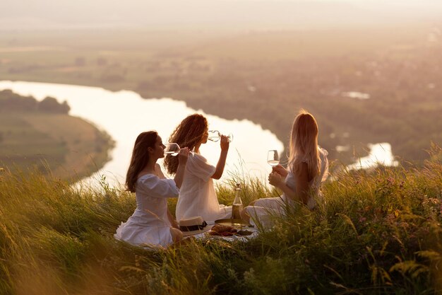 Foto vriendinnen hebben een picknick op de berg bij zonsondergang.