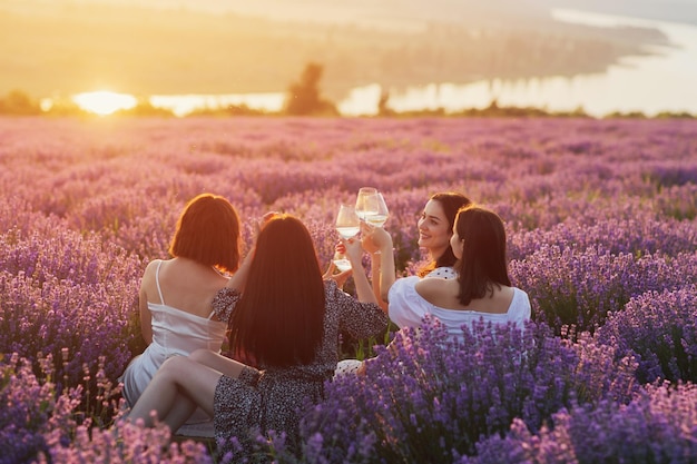 vriendinnen in jurken die picknicken en wijn drinken in het lavendelveld
