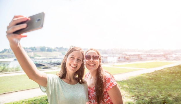 Vriendinnen nemen selfie samen plezier buitenshuis concept van moderne vrouwen vriendschap levensstijl vrouwelijke beste vrienden gelukkige meisjes reizen op pauze of stadsvakantie door de rivier heldere warme dag