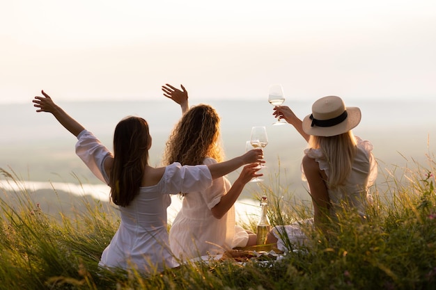 vriendinnen picknicken op de heuvel bij zonsondergang in de zomer