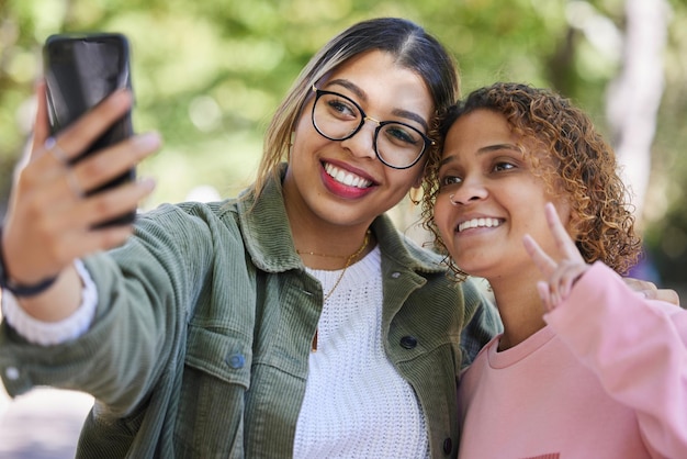 Foto vriendinnen selfie en vredesteken in het park met glimlachknuffel of samen voor geheugenblog of post op web meisje gen z studenten en blij voor profielfotofotografie of buiten voor sociaal netwerk