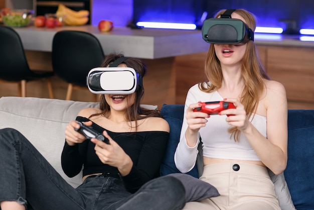 Vriendinnen spelen met opwinding videogames thuis met behulp van vr-brillen genieten van vakantietijd om