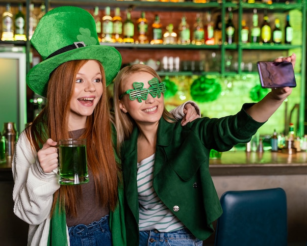 Vriendinnen vieren st. patrick's day aan de bar en samen selfie maken