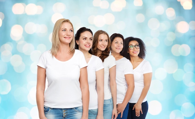 Foto vriendschap, divers, lichaamspositief en mensenconcept - groep gelukkige vrouwen van verschillende grootte in witte t-shirts over blauwe vakantielichten achtergrond