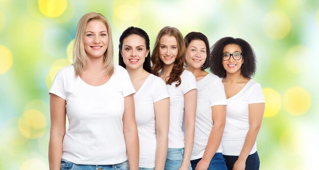 Foto vriendschap, divers, lichaamspositief en mensenconcept - groep gelukkige vrouwen van verschillende grootte in witte t-shirts over groene vakantie steekt achtergrond aan