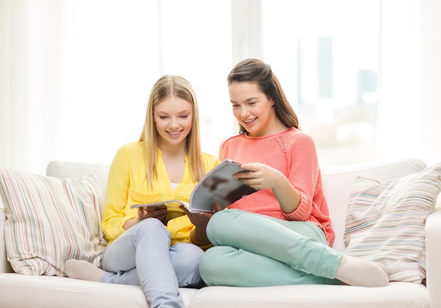 vriendschap en geluk concept - twee vriendinnen die thuis tijdschrift lezen