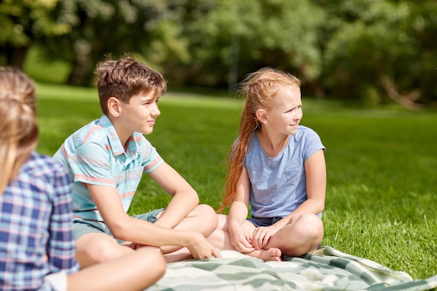 vriendschap, kindertijd, vrije tijd en mensenconcept - groep gelukkige kinderen of vrienden zittend op gras in zomerpark