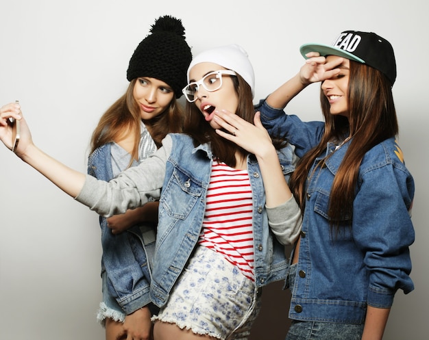 Vriendschap, mensen en technologieconcept - drie gelukkige tienermeisjes die met smartphone selfie nemen