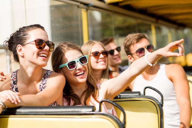 Foto vriendschap, reizen, vakantie, zomer en mensenconcept - groep glimlachende vrienden die met de tourbus reizen