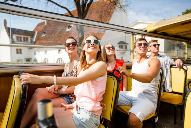 vriendschap, reizen, vakantie, zomer en mensenconcept - groep glimlachende vrienden die met de tourbus reizen