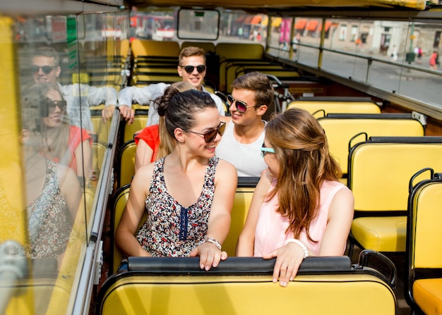 Foto vriendschap, reizen, vakantie, zomer en mensenconcept - groep lachende vrienden die met de tourbus reizen