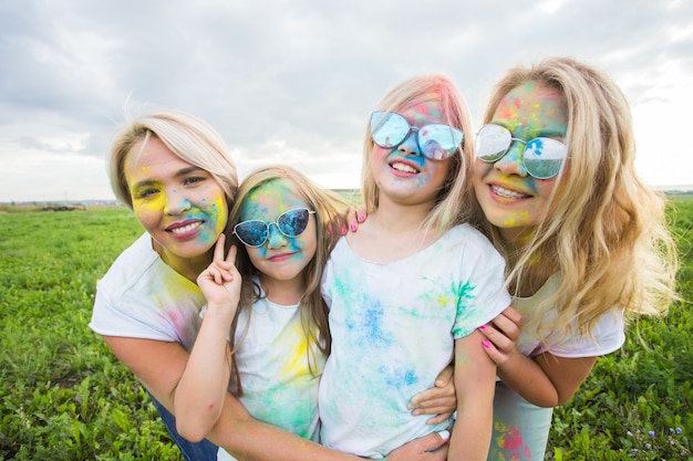 Vriendschap, vakantie, kleurenconcept - portret van mooie en gelukkige vrienden bedekt met verf