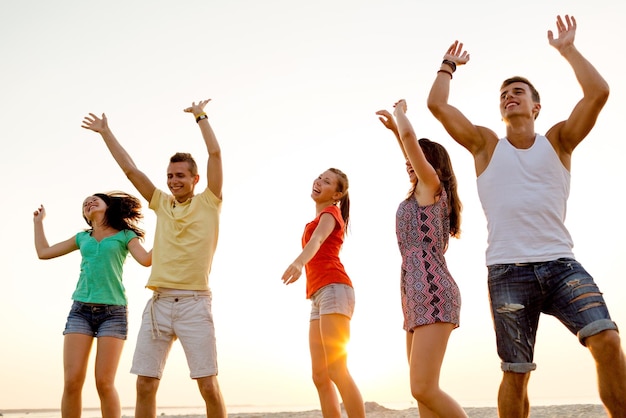 vriendschap, zomervakantie, vakantie, feest en mensen concept - groep lachende vrienden dansen op het strand