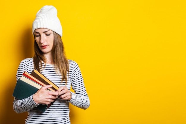 Vriendschappelijke jonge vrouw die een boek op een gele achtergrond leest