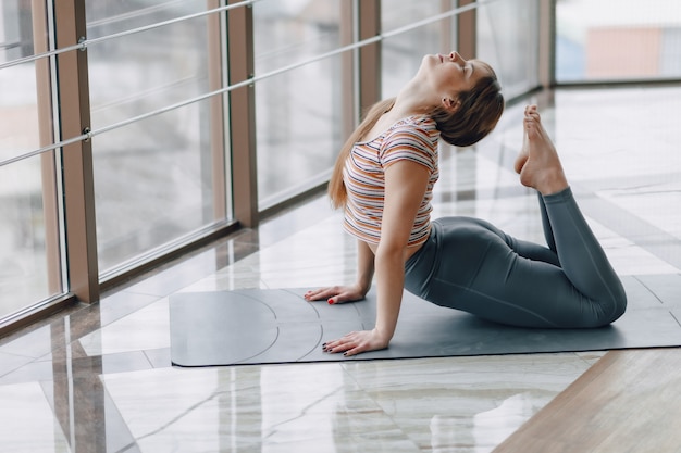 Vrij aantrekkelijk meisje dat yoga doet en in de heldere ruimte ontspant