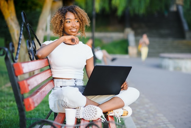 Vrij Afrikaanse Amerikaanse dame met een computer in het park