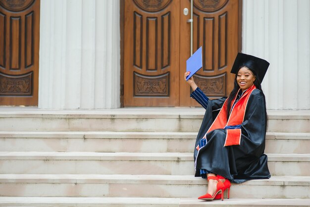 Vrij Afro-Amerikaanse vrouwelijke afgestudeerde buiten universiteitsgebouw